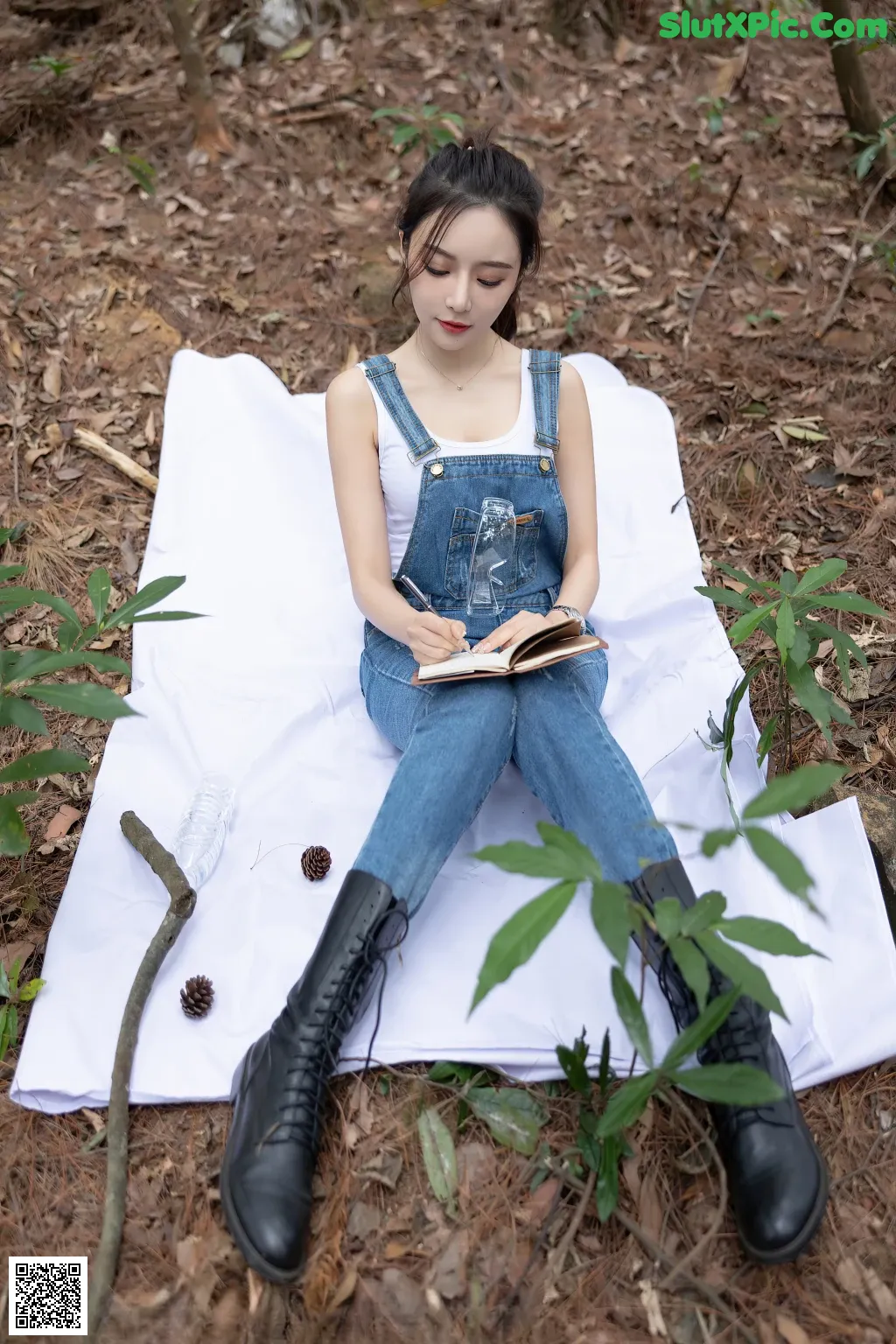 A woman sitting on a blanket in the woods.