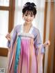 A woman in a pink and blue hanbok is posing for a picture.