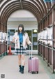 A woman with a pink suitcase walking down a hallway.