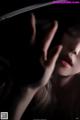 A woman with her hand on her face in the dark.