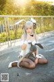 A woman in a bunny costume sitting on the ground with a stuffed animal.