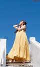 A woman in a yellow dress standing on some steps.