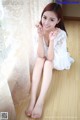 A woman sitting on the floor in a white dress.