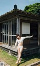 A woman in a white bikini standing in front of a house.