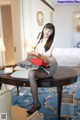 A woman sitting on top of a table in a hotel room.